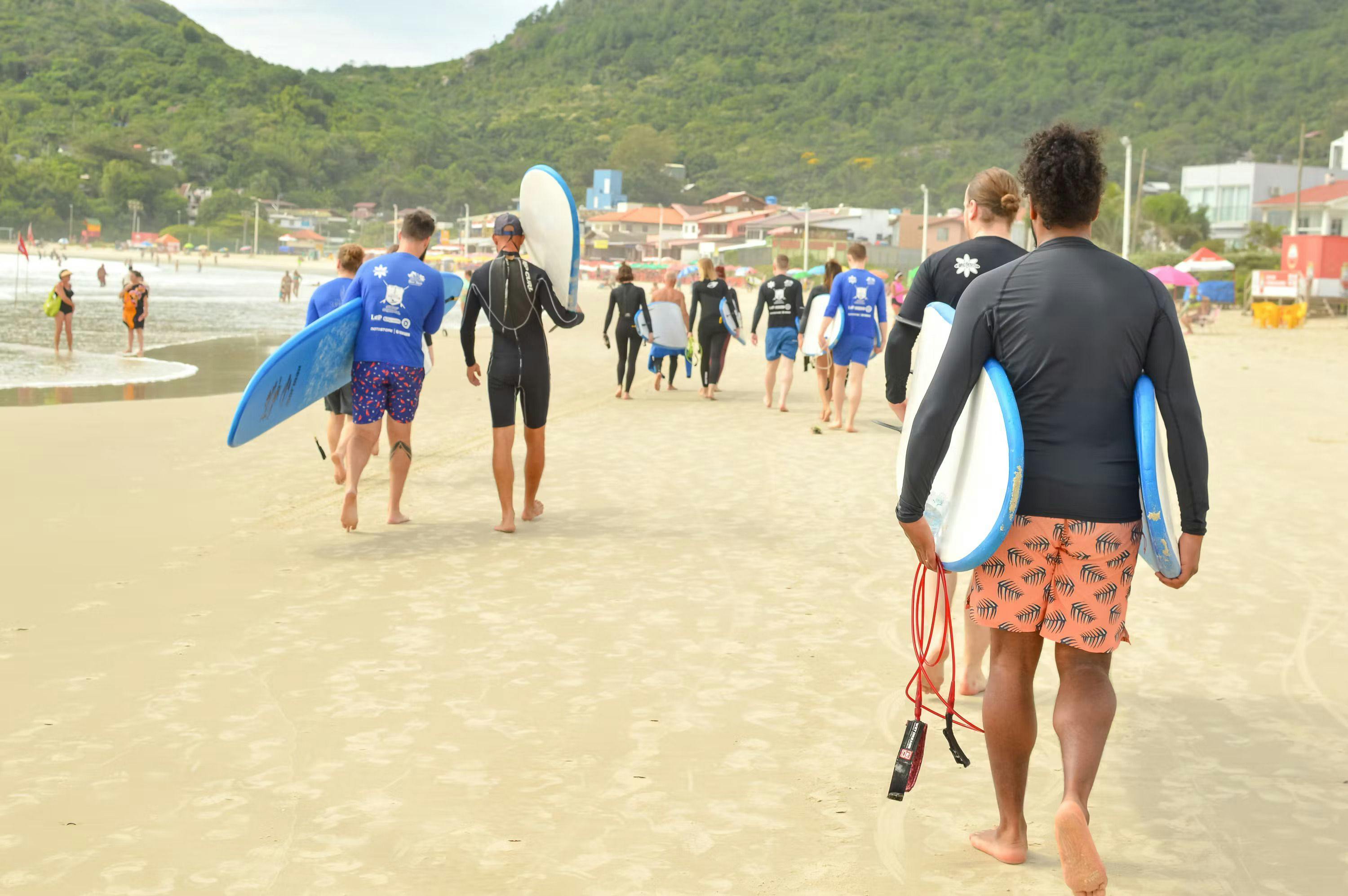 Team walking on the beach holding surf boards
